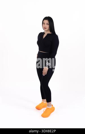 Sportliche Frau in schwarzem Outfit stehend und in die Kamera schaut Stockfoto
