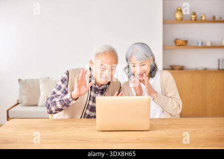 Seniorenpaar winkt während eines Videoanrufs zum Laptop Stockfoto