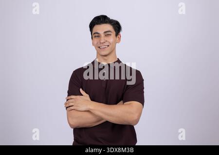 Junger Mann stand mit verschränkten Armen und lächelnd Stockfoto
