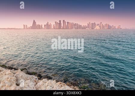 Moderne Skyline von Doha West Bay mit Wolkenkratzern und Gebäuden vor einem farbenfrohen Sonnenuntergang über dem Persischen Golf Stockfoto