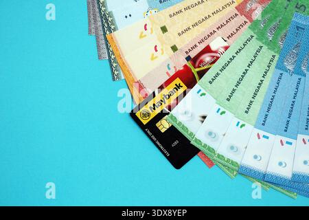 KIEW, UKRAINE - 28. JANUAR 2026 Maybank-Karte und malaysische Ringgit-Geldscheine auf dem Tisch in Nahaufnahme. Maybank ist die beliebteste Bank in Malaysia Stockfoto