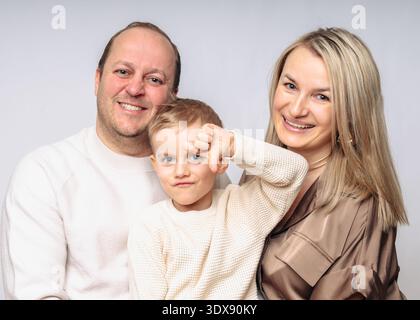Europäische glückliche Familie mit Sohn 4 Jahre alt, Studio von der Taille bis zur Taille geschossen, in beigen Farben auf weißem Hintergrund gekleidet, alle blonden Eltern 35-39 Jahre alt Stockfoto