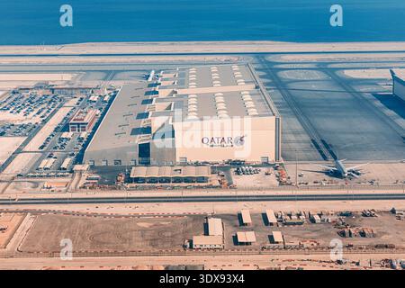 2. Dezember 2025, Doha, Katar: Qatar Airways Hangar mit Flugzeugen auf dem Asphalt und einem großen Parkplatz Stockfoto
