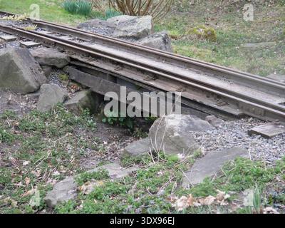 Kleine Überführung des Gleises einer Schmalspurbahn über einen Graben. Starke Holzdielen bilden die Brücke. Die Schienen sind stark mit Erde verschmutzt Stockfoto