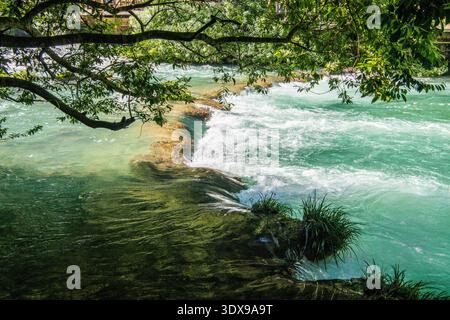 Klares türkisfarbenes Wasser, das über eine natürliche Kalksteinbarriere in Xiaoqikong Scenic Area, Libo County, Provinz Guizhou, China fließt. Stockfoto