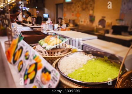 Thailändisches Essen im Food Court in Thailand - kochen und servieren Sie das beliebte thailändische Dessert Mango mit Kleberreis im thailändischen Khao Niao Mamuang. Reisstöcke: Stockfoto