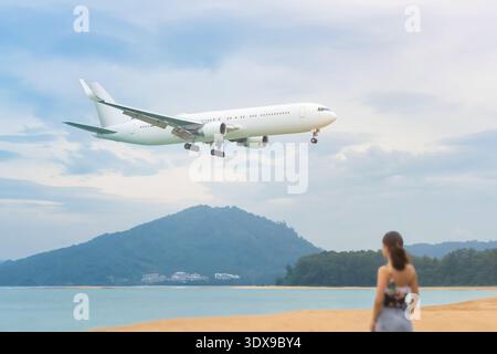 Ein großes weißes Flugzeug fliegt tief über den Strand, um Reisende oder Urlauber auf eine tropische Insel für einen fabelhaften Urlaub im besten Hotel zu bringen Stockfoto