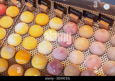 In einem Süßwarenladen werden verschiedene handwerkliche Mochi-Eissorten mit Mango-, Pfirsich-, Himbeer- und Karamell-Miso-Aromen angeboten Stockfoto