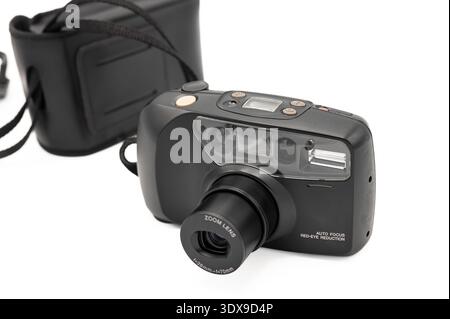 Vorderansicht einer klassischen schwarzen 35-mm-Kompaktkamera mit vollständig ausgezogenem Zoomobjektiv, integriertem Blitz und Originalgehäuse, isoliert auf einem Stockfoto