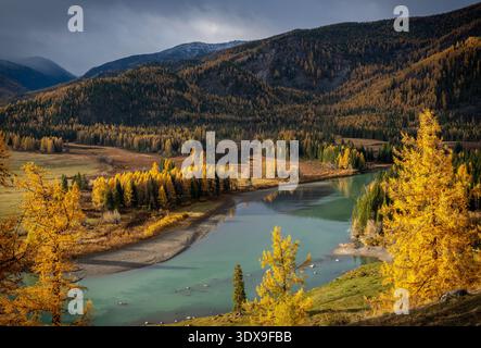 Majestätischer Blick auf einen ruhigen türkisfarbenen Fluss, der sich durch einen herbstlichen Wald in der Nähe von Bergen schlängelt. Stockfoto