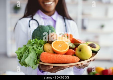 Health Professional hält einen Teller mit frischem Obst und Gemüse in einer klinischen Umgebung Stockfoto