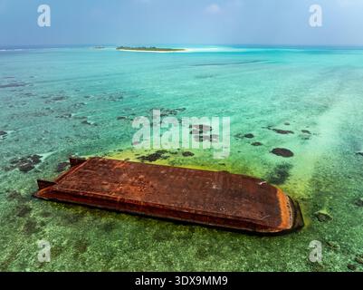 Aus der Vogelperspektive auf ein verwittertes Schiffswrack im türkisfarbenen Wasser, mit einer entfernten Insel, die einen Hauch von Ruhe verleiht, Hoarafushi, Thiladhunmathee UT Stockfoto