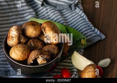 Frische braune Champignons in einer Keramikschale auf einem Holztisch. Stockfoto