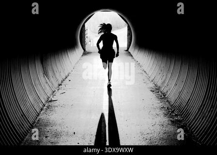 Eine junge Frau läuft durch einen Tunnel, während sie in Jackson, Wyoming trainiert. Stockfoto