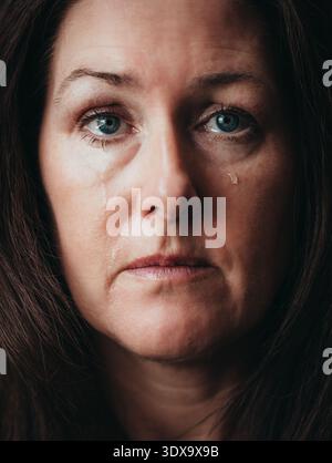 Nahaufnahme einer Frau, die weint und Tränen über ihr Gesicht laufen. Stockfoto