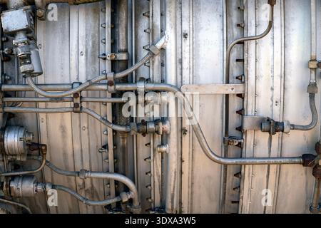 Nahaufnahme der Metallrohre und -Fittings an einer großen Maschine. Das Foto zeigt verschiedene Verbindungen und Strukturen in einer Werkstattumgebung. Es ist tagsüber und Stockfoto