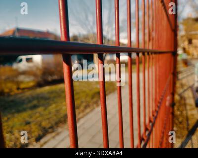 Ein hochwertiges Werbefoto eines roten Metallzauns in Budapest. Sie erfasst industrielle Texturen und urbane Perspektiven und repräsentiert Sicherheit, grenzenlos Stockfoto