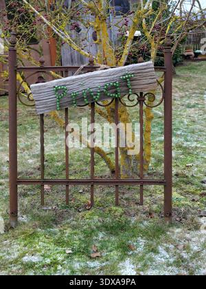 Verwittertes Holzschild mit dem Wort „privat“ aus grünen Ziernägeln auf einem alten Metallzaun in einem Wintergarten. Stockfoto