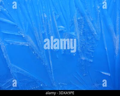 Frühfrosteisstruktur mit Radialkristallen in tiefblauem Blau – abstrakte Wintertextur mit natürlicher Bildung. Kopierraum. Stockfoto