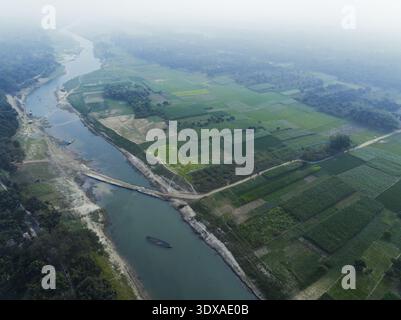 Aus der Vogelperspektive auf den ruhigen Fluss Padma, der durch üppige landwirtschaftliche Felder fließt, durch eine Brücke unter einem weichen, diffusen Licht, Rajshahi, Rajshahi Stockfoto