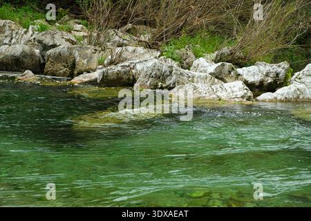 Türkisfarbenes Wasser im Bergfluss, Strömung, felsiges Ufer. Stockfoto