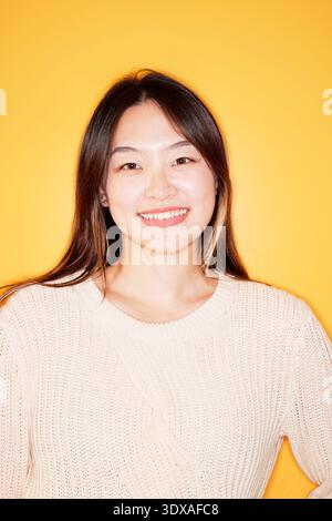 Porträt einer schönen jungen Frau, die an der gelben Wand steht Stockfoto