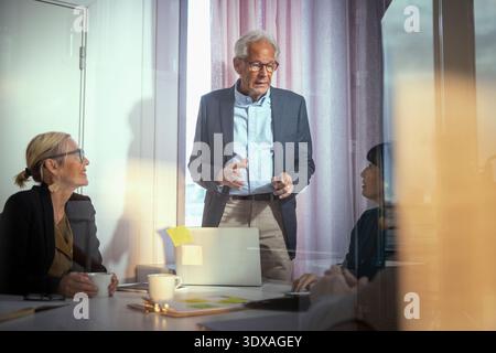 Senior männlicher Manager, der das Team im Besprechungsraum im Büro unterstützt Stockfoto