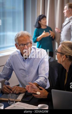 Hochwinkelansicht eines Geschäftsmannes, der weiblichen Kollegen zuhört, während er im Büro sitzt Stockfoto