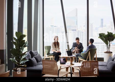 Junge Unternehmerinnen sitzen mit männlichem Manager im Amt Stockfoto