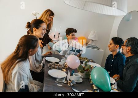 Glückliche Familie feiert Geburtstag, während sie zu Hause am Esstisch sitzt Stockfoto
