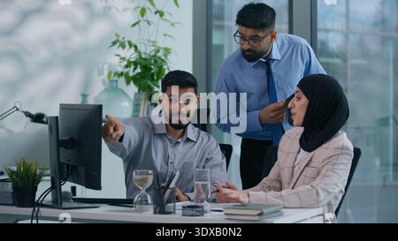 Drei Geschäftskollegen. Geschäftsmann mit islamischer Geschäftsfrau diskutieren über reden, arbeiten, Computer aussehend, Arabisch-Mann-Chef kommt ins Amt Stockfoto