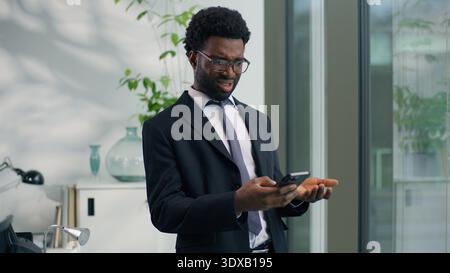 Afroamerikanischer Geschäftsmann verwirrt enttäuscht enttäuscht verärgert Kerl Handy irritiert Tippen Chat Smartphone Geschäftsmann männlich hält Handy Stockfoto