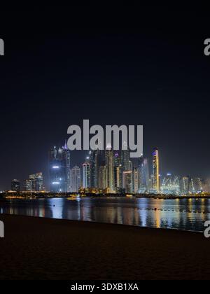 Vertikale Skyline der Dubai City Wolkenkratzer bei Nacht, beleuchtete Skyline mit magischen Reflexen auf der Marina Uferpromenade. Stockfoto