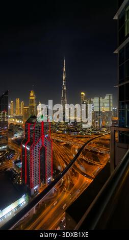 Skyline von Dubai bei Nacht mit Burj Khalifa und Maze Tower, leuchtenden Highways und Wolkenkratzern, schnellem urbanen Leben in einer intelligenten Stadt der Zukunft. Stockfoto