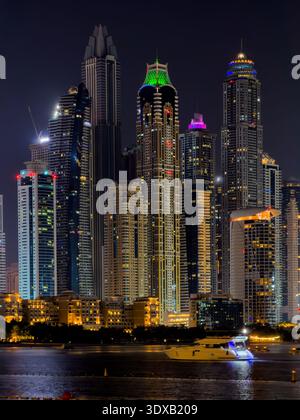 Nahaufnahme der Stadt Dubai bei Nacht, beleuchtete Skyline mit magischen Reflexen auf der Marina Uferpromenade. Teleaufnahmen Stockfoto