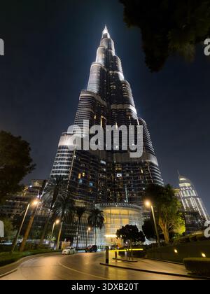 Weltberühmtes Wahrzeichen in Dubai, der berühmte Wolkenkratzer Burj Khalifa, glitzert vor einem klaren, nächtlichen Stadthimmel. Stockfoto