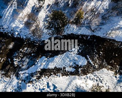 Aus der Vogelperspektive auf die dunkle Erde im Kontrast zur unberührten schneebedeckten Landschaft in der Nähe von Kuznice in den Tatra-Bergen, Zakopane, Wojewodzt Stockfoto