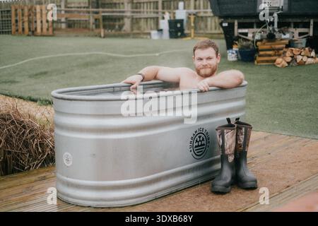 Ein Mann sitzt in einer Badewanne mit einem Schild mit der Aufschrift "Unbefleckte Empfängnis" Stockfoto