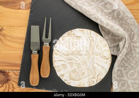 Brie Käse auf einem Schieferstein auf Holztisch, Nahaufnahme. Draufsicht. Stockfoto