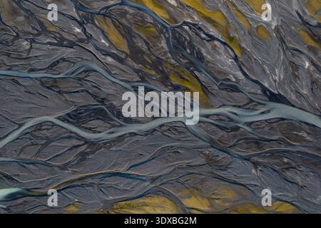 Aus der Vogelperspektive ziehen sich Gletscherflüsse durch die krasse, kontrastreiche Landschaft und enthüllen einen Wandteppich aus grauer und goldener Erde, Island. Stockfoto