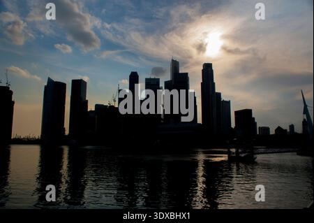 Singapur, 10. Januar 2020: Dramatischer Sonnenuntergang über der Skyline von Singapore Marina Bay mit Silhouetten von CBD-Wolkenkratzern, die sich an der ruhigen Uferpromenade spiegeln. Leistungsstarker Konnektor Stockfoto