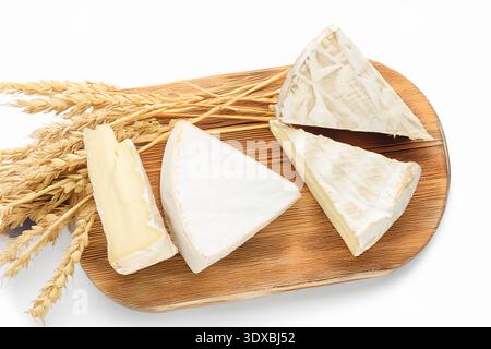 Brie-Käse mit Küchenutensilien auf einem hölzernen Küchenbrett, isoliert auf weißem Hintergrund, Nahaufnahme, Blick von oben. Stockfoto