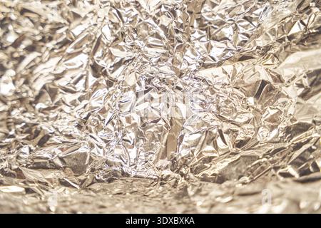Zerknitterte reflektierende silberne Aluminiumfolie für eine strukturierte Metallic-Oberfläche mit Lichtreflexionen. Stockfoto