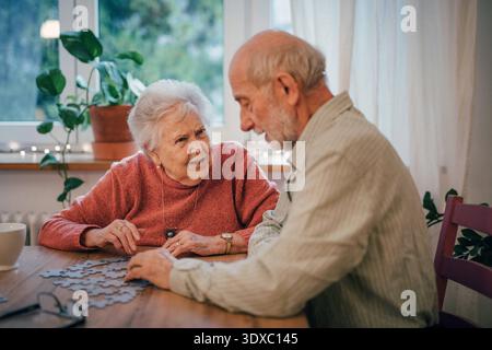 Seniorenpaar lösen gemeinsam Puzzle zu Hause. Seniorenpaar lösen gemeinsam Puzzle zu Hause. Kognitive Gesundheit. Modell freigegeben Stockfoto
