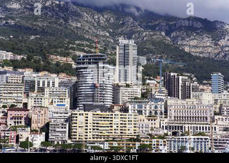 Panorama-Skyline von Monte Carlo Monaco mit modernen Hochhäusern, dichten Gebäuden und felsigen Bergen unter bewölktem Himmel. Monte Carlo, Monaco Stockfoto