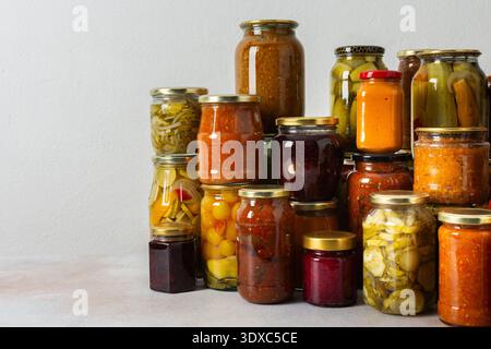 Canning ist eine häufige Aktivität in der Küche, da die Theke mit Gemüse und Obst gefüllte Gläser säumen. Diese Praxis hilft dabei, Lebensmittel für den Gewinn zu bewahren Stockfoto