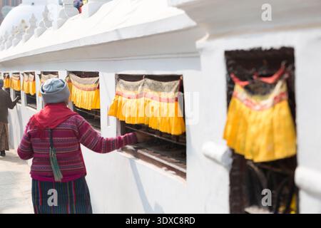 Der Gläubige spinnt eine Reihe traditioneller tibetischer Gebetsmühle am Fuße der Boudhanath Stupa in Kathmandu, Nepal. Stockfoto