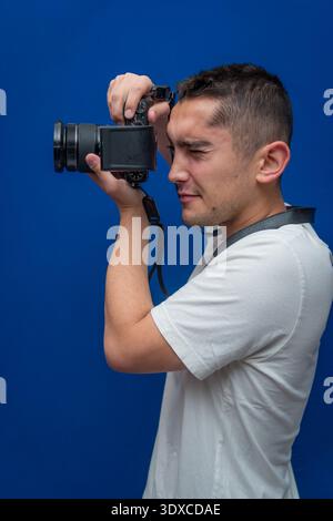 Fotograf hält eine Kamera und fokussiert sich auf ein Motiv. Er demonstriert Geschicklichkeit und Leidenschaft für visuelles Erzählen und Fotografieren Stockfoto