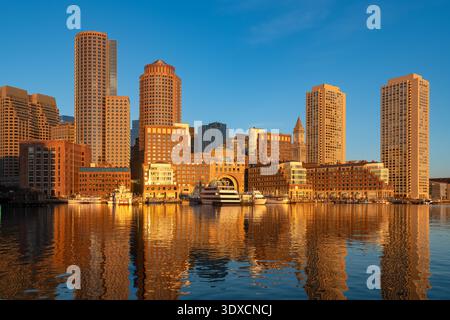 Die Skyline von Boston wird durch das goldene Morgenlicht des Sonnenaufgangs über dem Hafen beleuchtet. Stockfoto