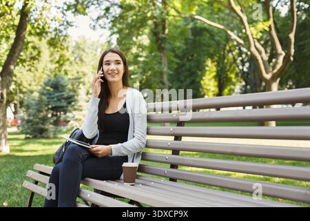 Collage einer Frau, die auf einer Parkbank sitzt und telefoniert und einen Kaffee genießt Stockfoto